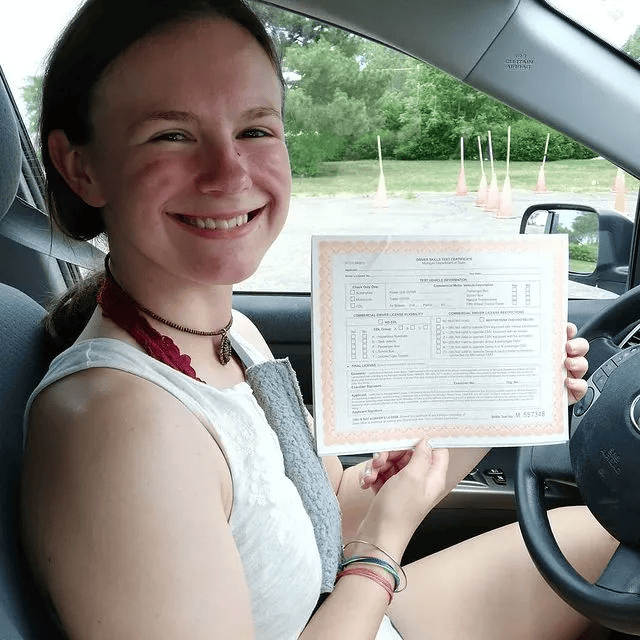 A girl inside car showing certificate